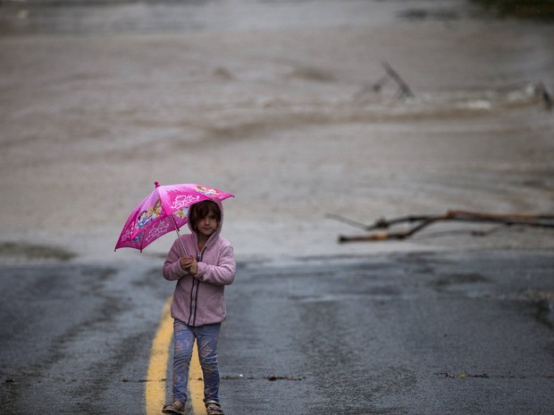 Criança se protege da chuva em meio a alagamento em Austin, Texas, neste sábado (24) (Foto: REUTERS/Adrees Latif)
