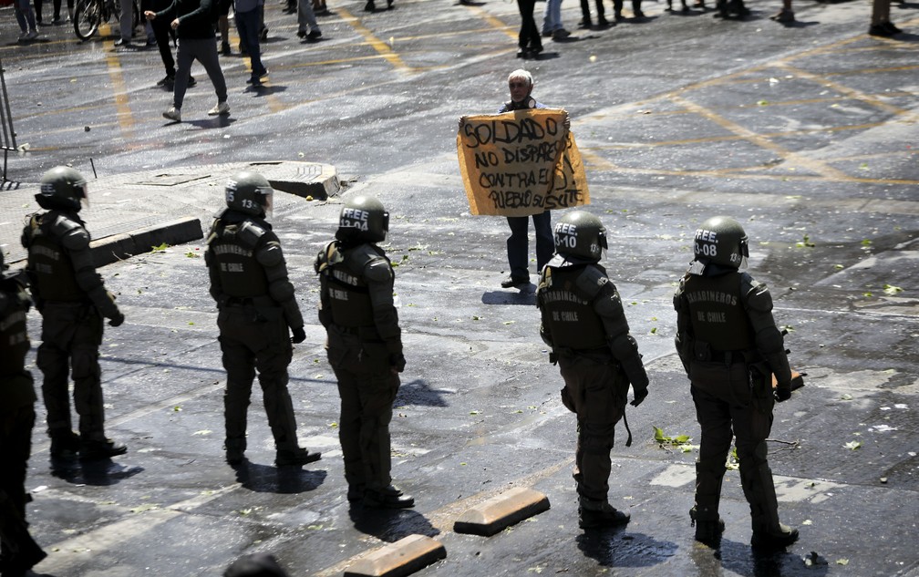 'Soldado, não dispare contra as pessoas', pede o cartaz de um manifestante em Santiago nesta quarta-feira (23), mais um dia de protestos no Chile — Foto: Rodrigo Abd/AP Photo