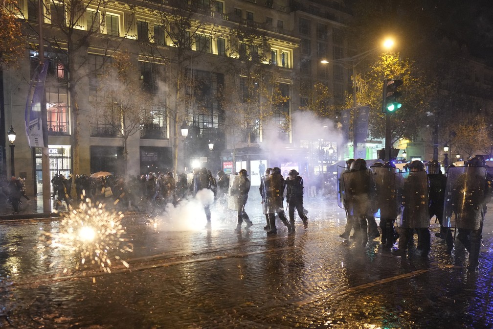 Policiais de choque são atacados com fogos de artifício na avenida Champs-Elysees, em Paris, após derrota da França na final da Copa do Mundo em 18 de dezembro de 2022 — Foto: Thibault Camus/AP