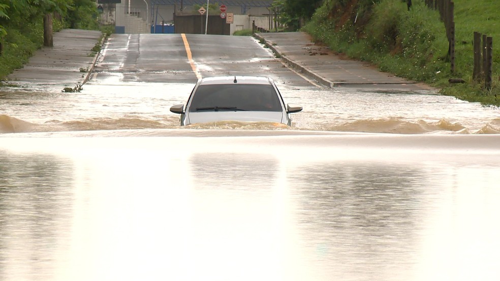 Carro praticamente submerso pela água em trecho de estrada em Viana, ES — Foto: Reprodução/TV Gazeta