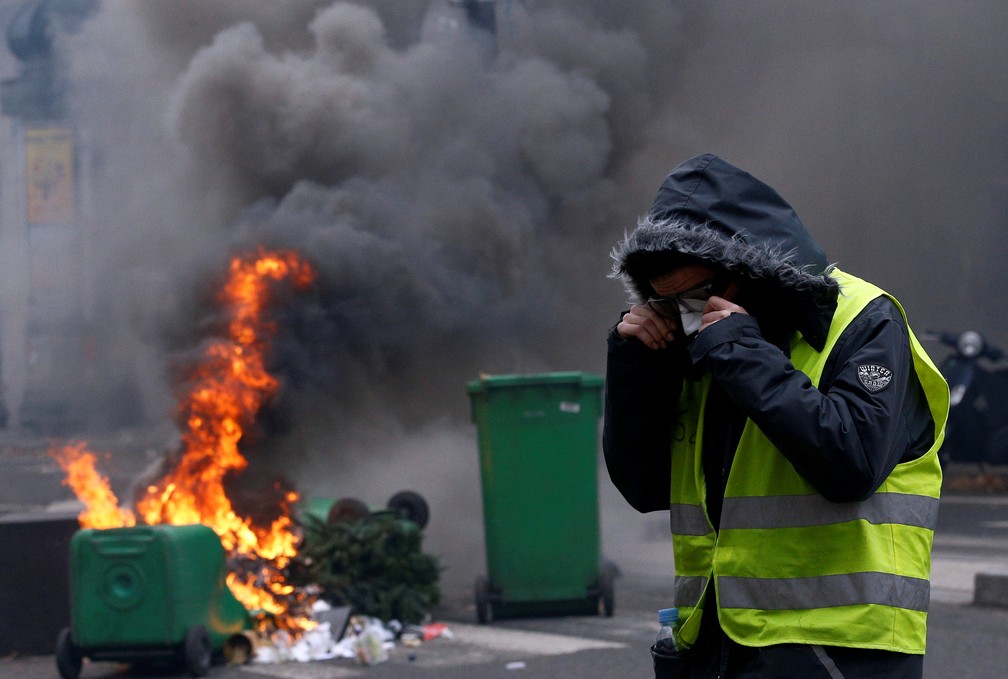 Manifestante protege o rosto da fumaÃ§a durante confrontos com a polÃ­cia em Paris, no sÃ¡bado (8). â Foto: Stephane Mahe/Reuters