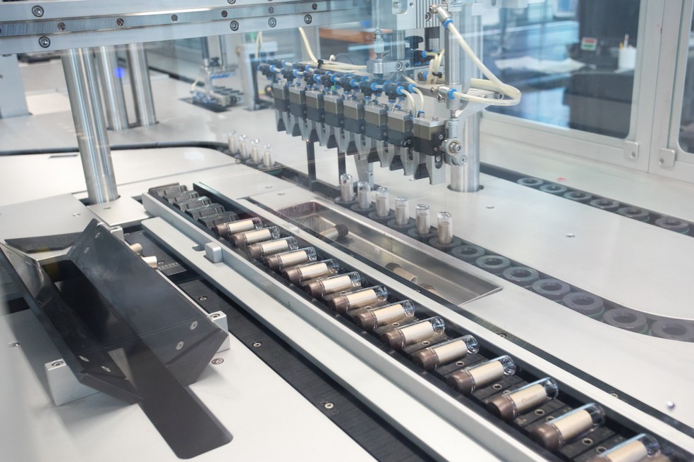 Depois de tampados, os batons seguem deitados pela esteira. (Foto: Celso Tavares/G1)