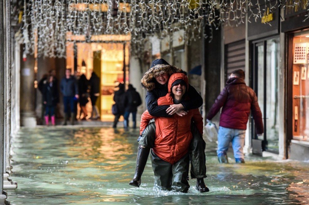 Turistas caminham em ruas alagadas de Veneza neste domingo (24) — Foto: Miguel Medina/AFP