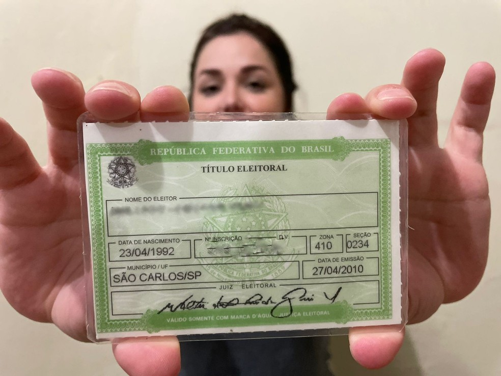 Mulher segurando o título de eleitor em São Carlos — Foto: Ana Marin/g1