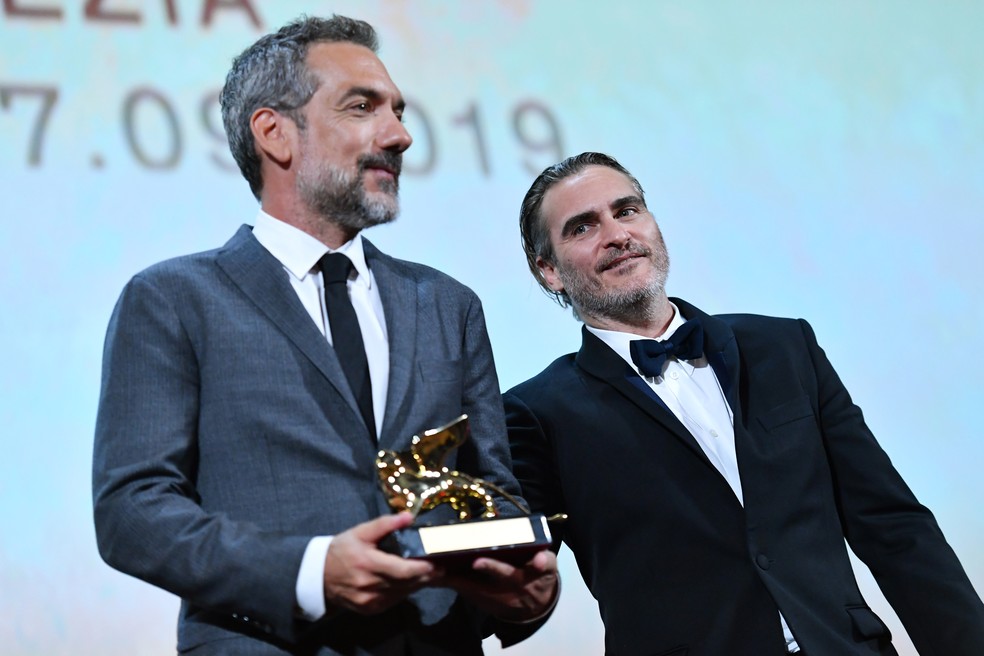 O diretor americano Todd Phillips recebe o LeÃ£o de Ouro por seu filme "Coringa"; ao lado, o ator Joaquin Phoenix, que interpreta o vilÃ£o â€” Foto: Alberto Pizzoli/ AFP