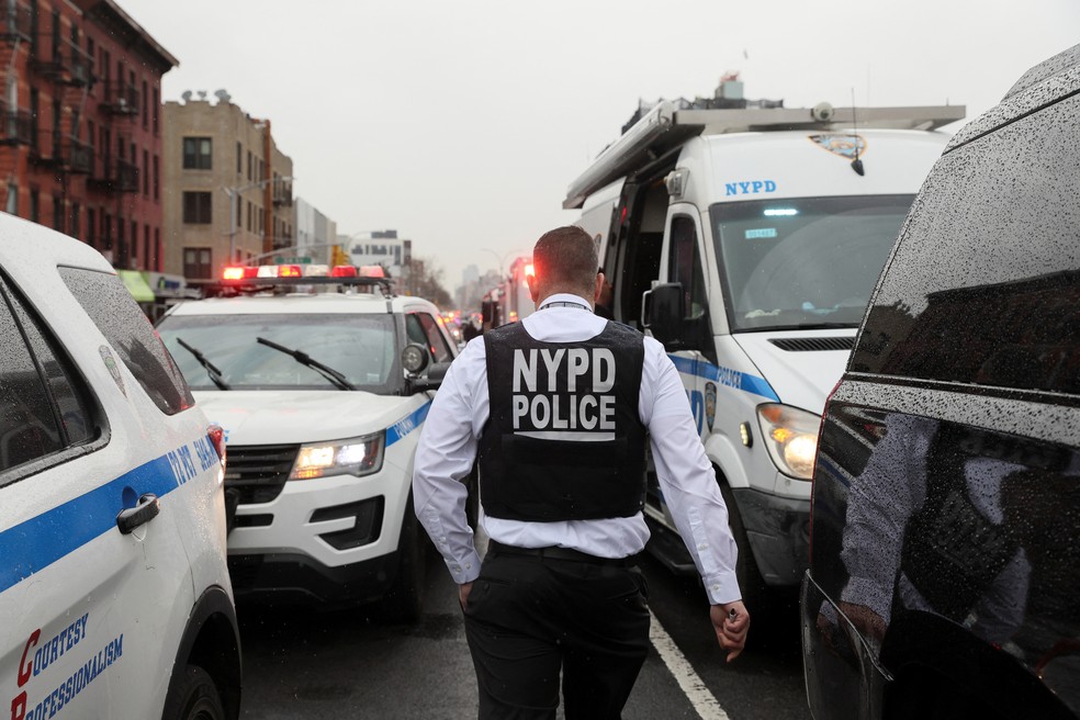 Policial caminha entre carros em estação de metrô do Brooklyn, onde dezenas foram baleados, segundo Corpo de Bombeiros da cidade.  — Foto: Brendan McDermid/Reuters