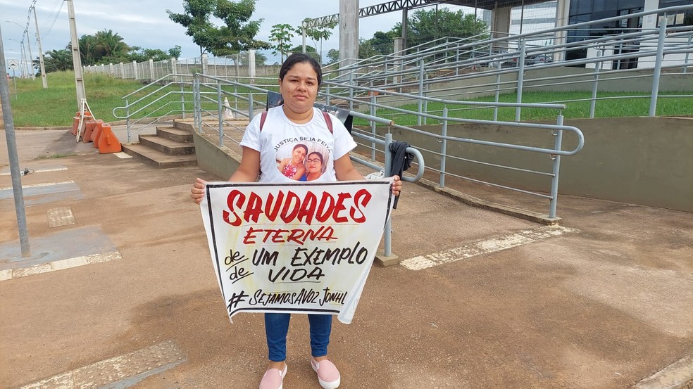 Irmã de Jonhliane Paiva com cartaz em frente à Cidade da Justiça antes do júri começar — Foto: Eldérico Silva/Rede Amazônica Acre 