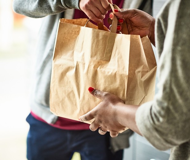 Woman holding paper bag with take out food, home delivery, food order, takeaway (Foto: Getty Images)