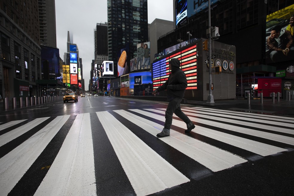 Homem atravessa rua vazia perto da Times Square, em Nova York, em meio à pandemia do novo coronavírus nos EUA — Foto: Mark Lennihan/AP