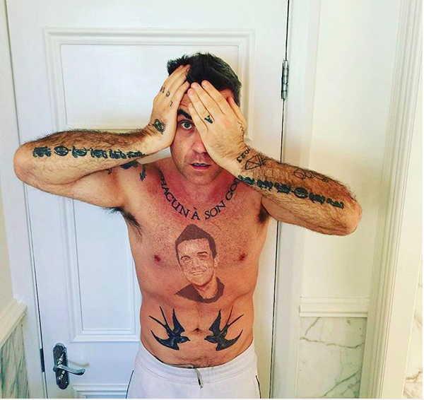 O cantor Robbie Williams com a tatuagem do próprio rosto na barriga (Foto: Instagram)