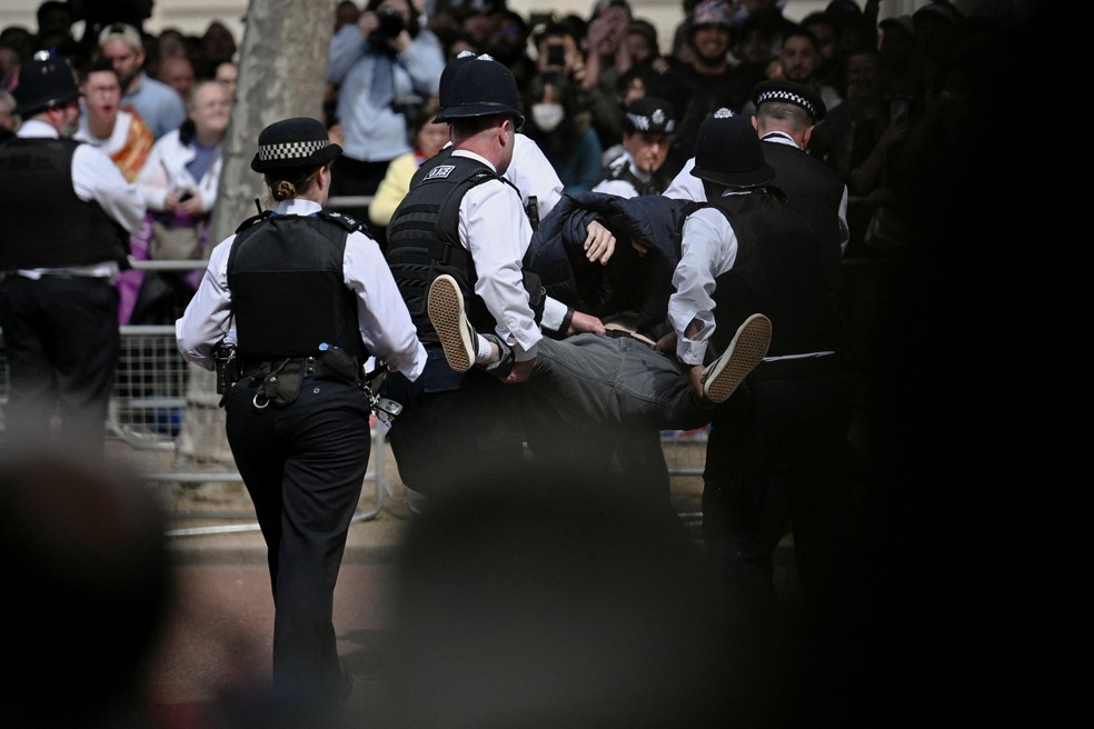 Pessoa é carregada pela polícia britânica para fora do desfile em homenagem ao Jubileu da Rainha — Foto: Dylan Martinez/REUTERS