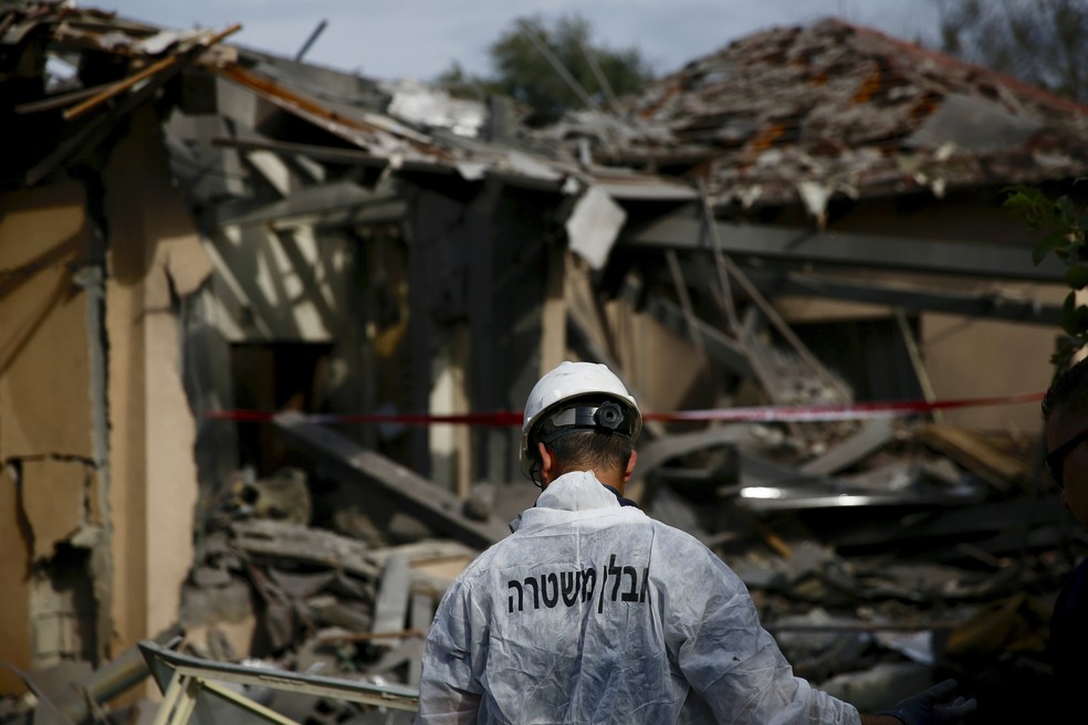 Policial israelense inspeciona casa atingida por foguete em Mishmeret, na região central de Israel, nesta segunda-feira (25) — Foto: Ariel Schalit/AP