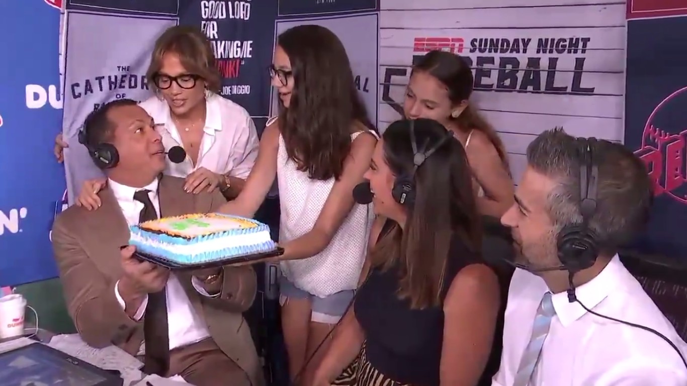 O instante no qual Alex Rodriguez é surpreendido por Jennifer Lopez e as duas filhas dele com um bolo durante a transmissão do jogo de beisebol que ele estava comentando (Foto: Twitter)
