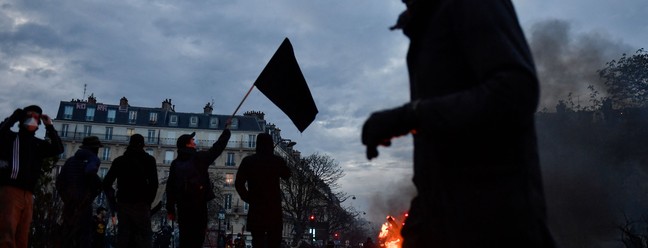 Manifestante passa por patinetes em chamas durante protesto em Paris, em 28 de março de 2023 — Foto: JULIEN DE ROSA / AFP