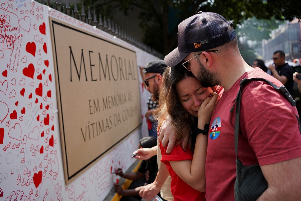 Pessoas se emocionam diante de memorial para as vítimas de Covid montado na Avenida Paulista, em São Paulo — Foto: Mariana Greif/Reuters