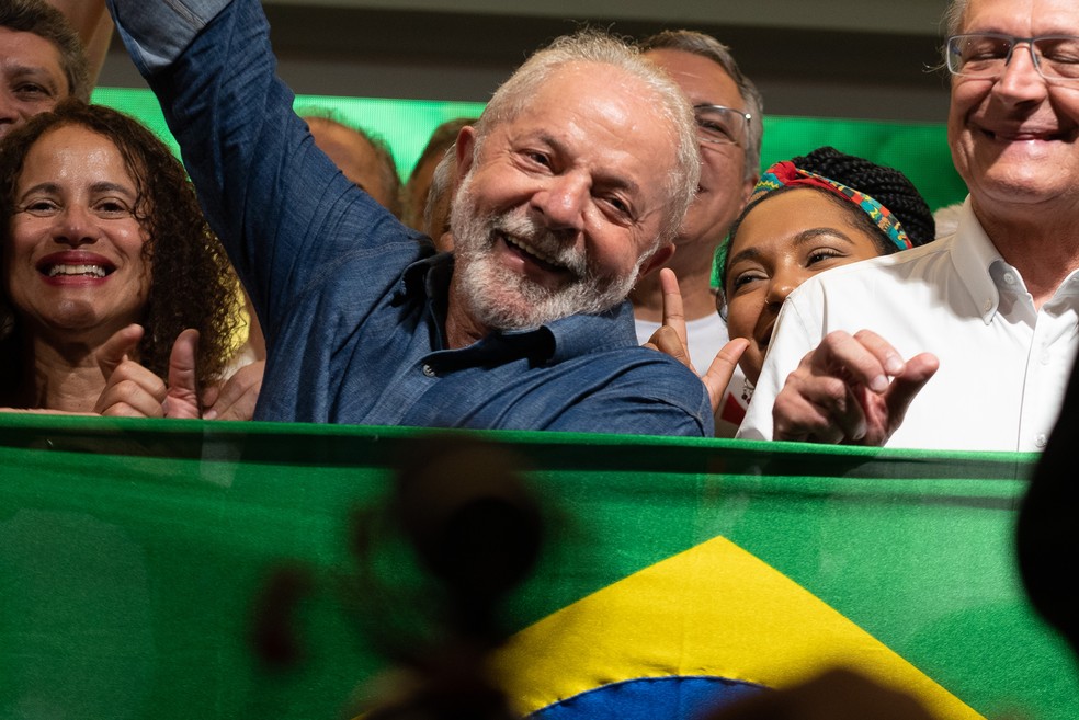 Lula sorri junto à bandeira do Brasil após vitória no 2º turno da eleição presidencial. — Foto: Fabio Tito / g1