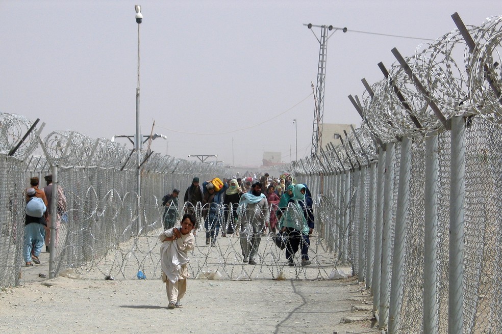 Pessoas cruzam o Portão da Amizade na cidade de Chaman, na fronteira entre Paquistão e Afeganistão, em 15 de agosto de 2021. — Foto: Saeed Ali Achakzai/Reuters