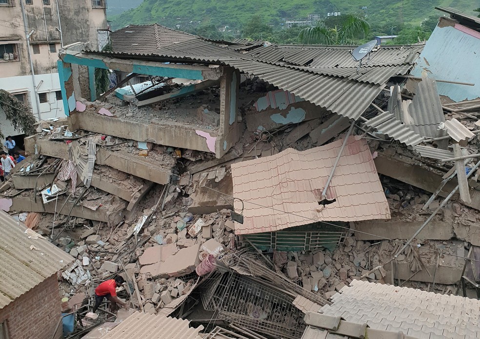 Homem tenta remover entulho após desabamento de prédio na Índia nesta segunda-feira (24) — Foto: Stringer/Reuters