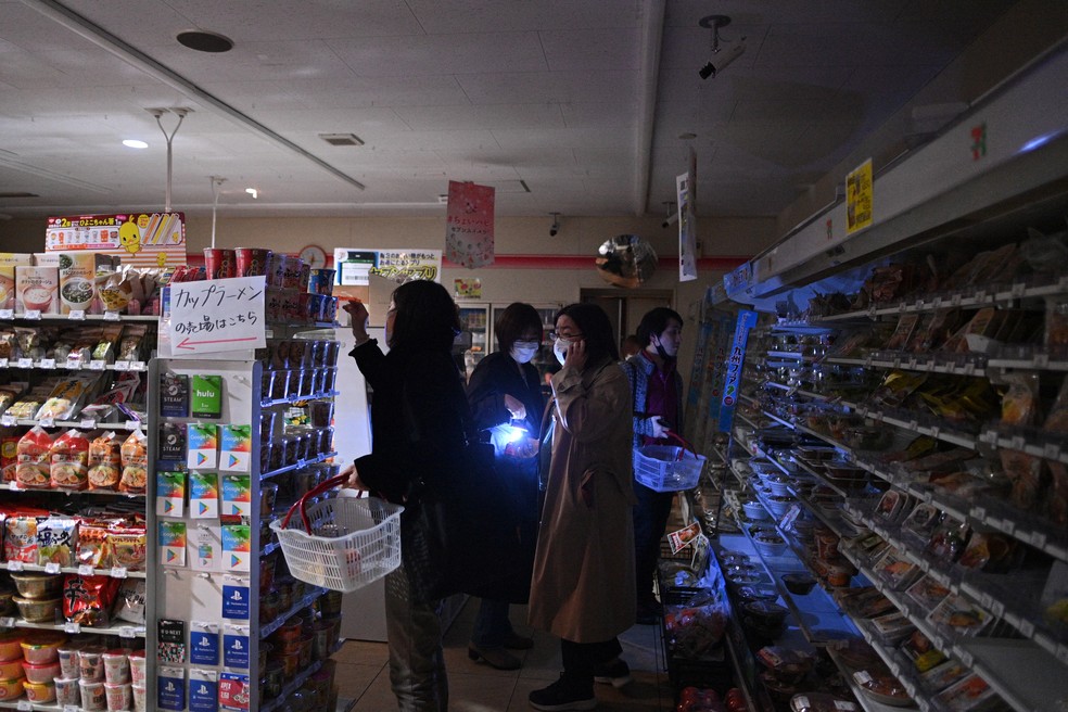 Clientes fazem compras em mercado durante apagão de energia no distrito de Koto, em Tóquio, no dia 16 de março de 2022, após um terremoto atingir a região de Fukushima, no Japão — Foto: Philip Fong/AFP