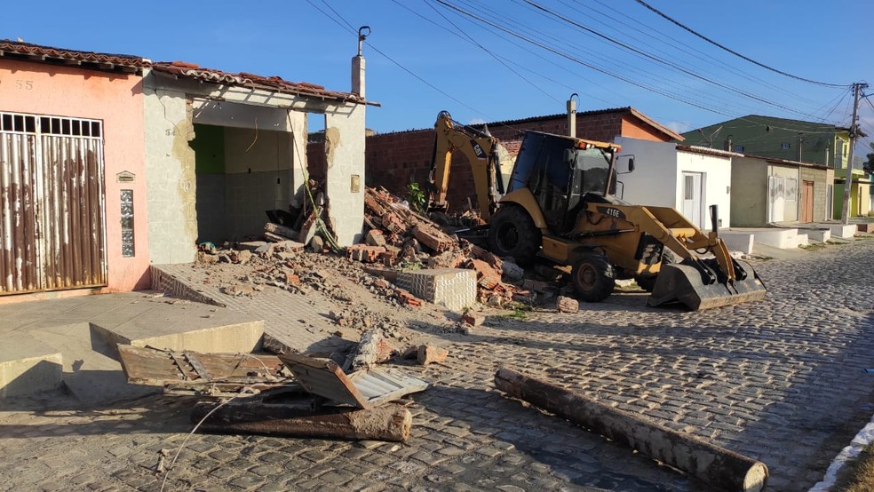 Retroescavadeira derruba muro durante operação em Mossoró, na manhã desta segunda-feira (25). No chão, canos que reforçavam o portão do local — Foto: Isaiana Santos/Inter TV Costa Branca