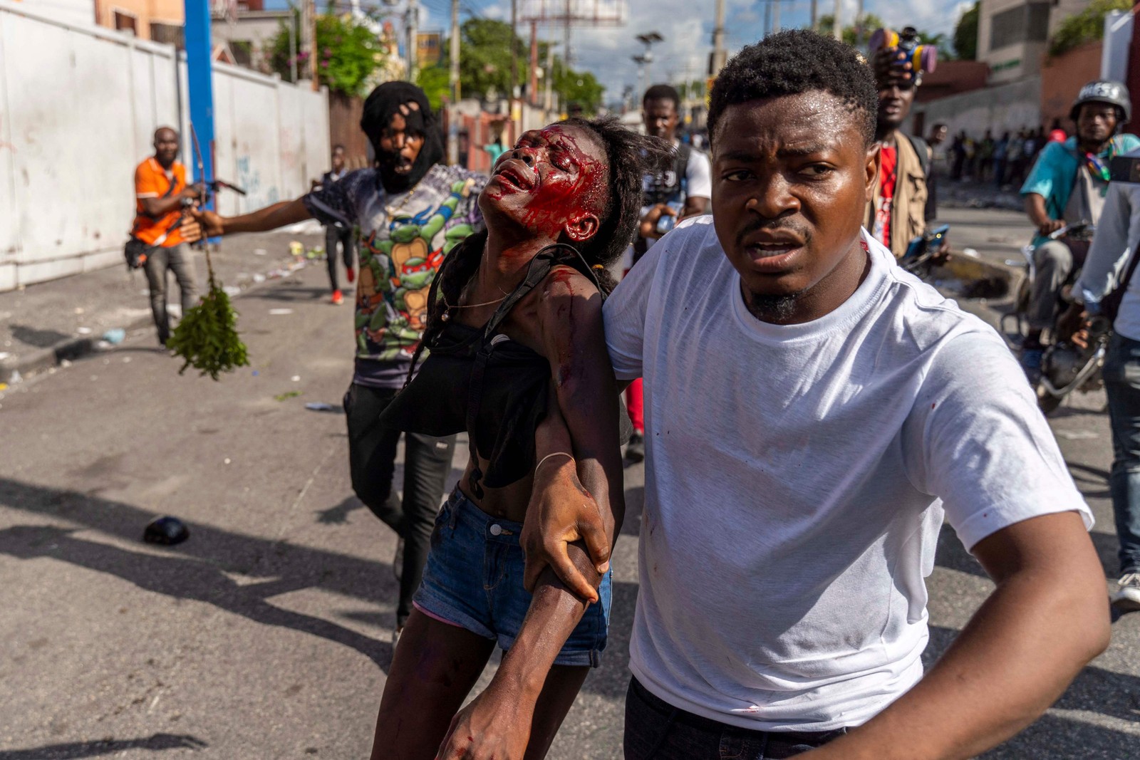 Homem ajuda uma mulher ferida durante protesto contra o primeiro-ministro haitiano, Ariel Henry, em Porto Príncipe, em 10 de outubro — Foto: Richard Pierrin / AFP