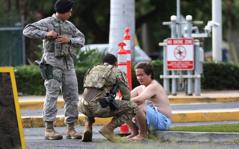 Forças de segurança atendem a um homem do lado de fora do portão principal de Pearl Harbor — Foto: Caleb Jones / AP Photo
