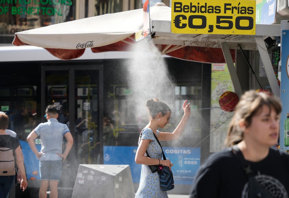Um cliente sob um spray de névoa refrescante em um quiosque de rua durante altas temperaturas no centro de Madri