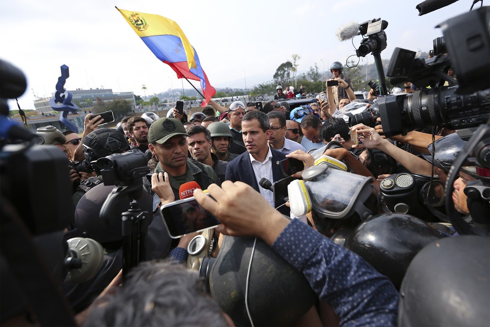 Juan Guaidó caminha em meio a apoiadores ao lado de um militar que comanda o grupo que o defende, antes de falar com a imprensa em Caracas — Foto: Fernando Llano/AP