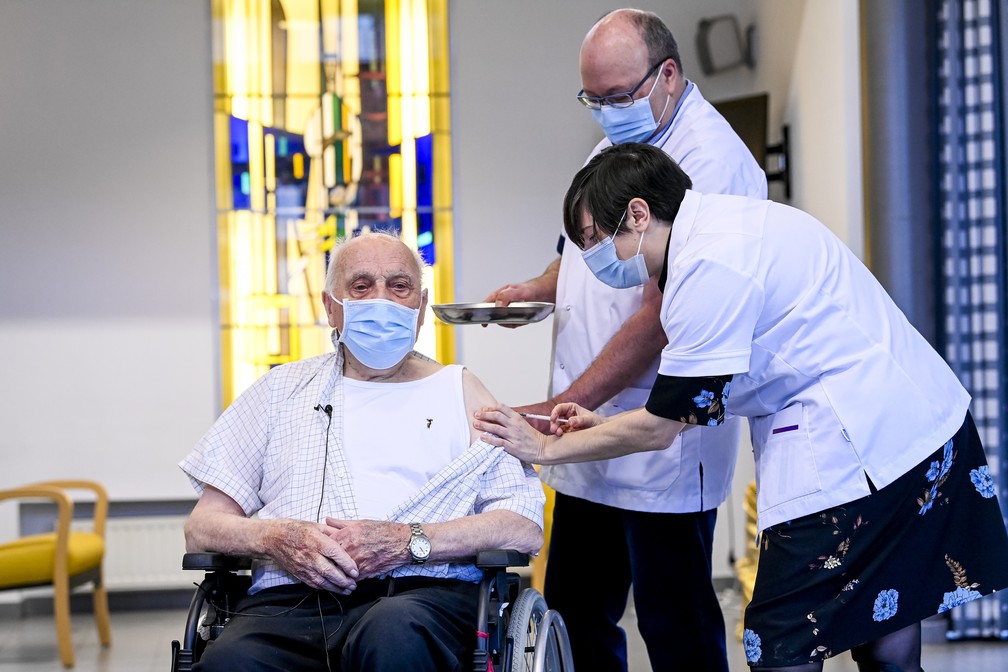 Foto mostra Jos Hermans, de 96 anos, recebendo a vacina da Pfizer/BioNTech contra a Covid-19 em Puurs, 30 km ao norte de Bruxelas, na Bélgica, nesta segunda-feira (28). Ele foi o primeiro belga a receber a vacina. — Foto: Dirk Waem / POOL / AFP