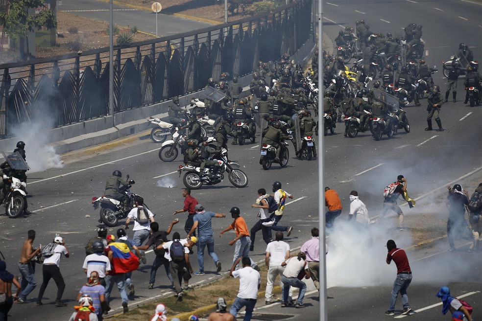 Oponentes ao governo de Nicolás Maduro entram em confronto com militares diante da base aérea 'La Carlota', em Caracas — Foto: Fernando Llano/AP