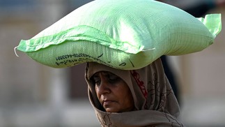 Mulher carrega um saco de farinha de trigo depois de comprar a preços controlados pelo governo em Islamabad, Paquistão — Foto: Aamir QURESHI / AFP