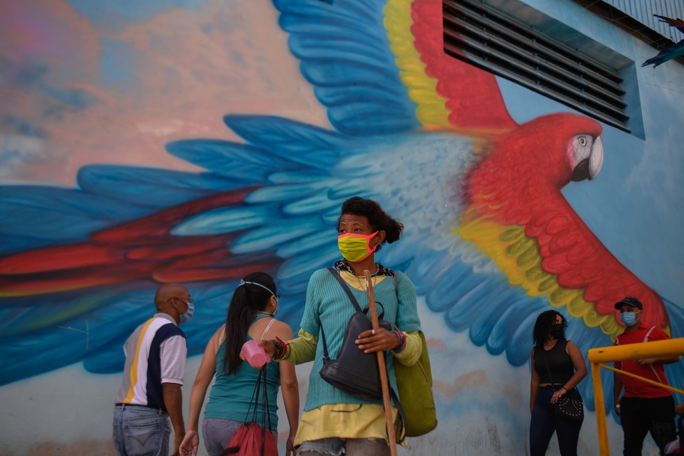 Uma mulher é vista utilizando uma máscara facial enquanto caminha pelo bairro de Petare em Caracas, na Venezuela, na segunda-feira (13) — Foto: Federico Parra/AFP