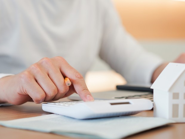 close up young man hand press on calculator to check and summary expense of home loan mortgage for refinance plan , people lifestyle concept (Foto: Getty Images/iStockphoto)