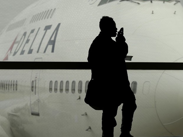 Passageiro fala ao celular antes de embarcar em voo (Foto: Charlie Riedel/AP)