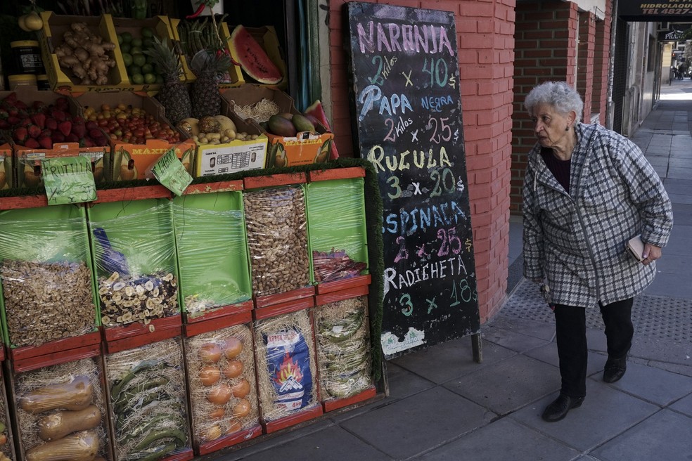 Mulher caminha em frente a venda de alimentos em Buenos Aires; Argentina vive momento de inflação descontrolada — Foto: Eitan Abramovich/AFP