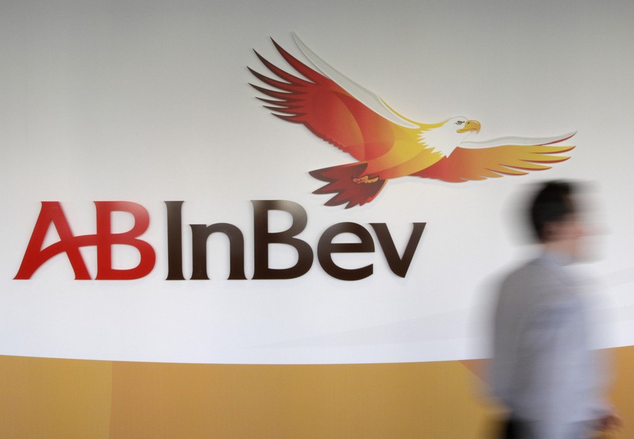 A man walks past the AB InBev logo as CEO Carlos Brito addresses the media to announce the 2010 year results, in Leuven, Belgium, Thursday, March 3, 2011. The world's largest brewer Anheuser-Busch InBev says its fourth-quarter net profit dropped 24 percen