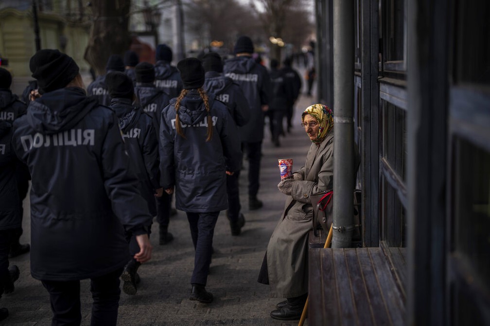 Policiais ucranianos passam por uma mulher pedindo esmolas em Odessa, Ucrnia, no domingo, 20 de fevereiro de 2019.  Foto: AP Foto/Emilio Morenatti
