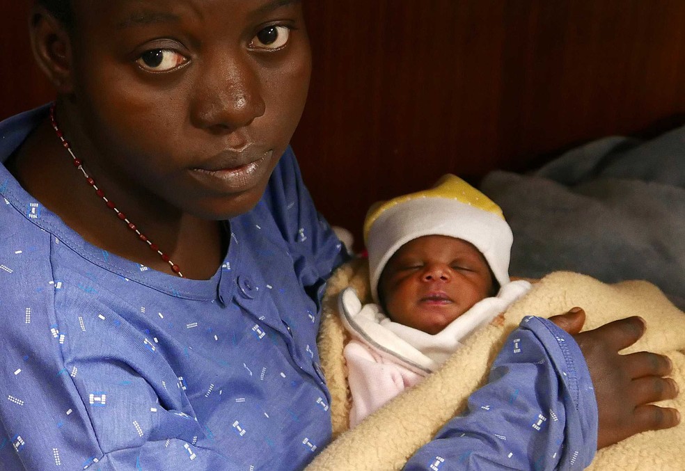 Nigeriana Miriam Ohene segura bebê no colo após ser resgatada durante a travessia no Mediterrâneo (Foto: Yannis Behrakis/ Reuters)