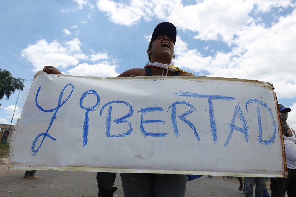 Mulher segura uma faixa que diz "Liberdade" em Pacaraima (RR), na fronteira Venezuela com o Brasil — Foto: Bruno Kelly/Reuters