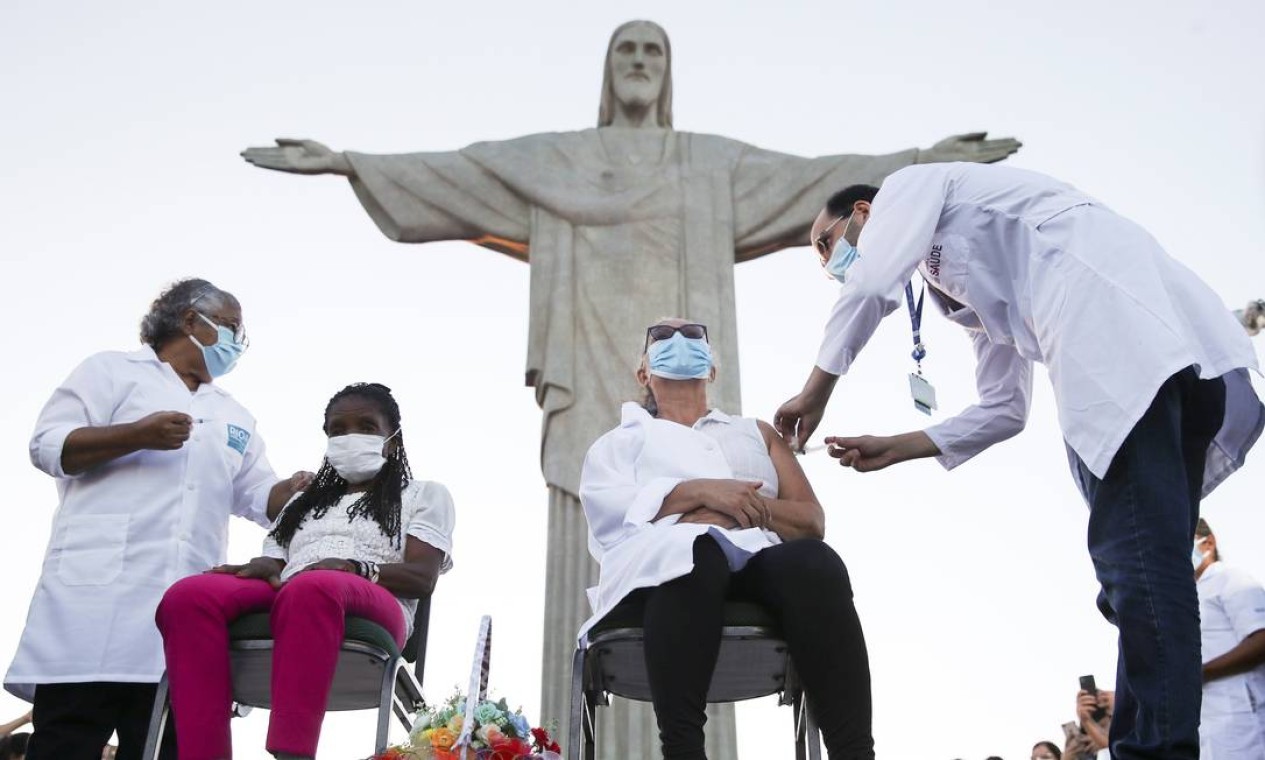 Dulcineia da Silva Lopes, 59 anos, recebe vacina CoronaVac diante da estátua do Cristo Redentor, no Rio de Janeiro. Ela e Therezinha da Conceição, de 80 anos, foram as primeiras moradoras do Rio a receberem a vacina — Foto: Ricardo Moraes / Reuters