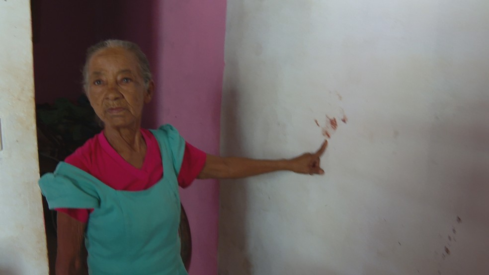 Judite Alves dos Santos, mãe da 28ª vítima de feminicídio no DF, mostra manchas de sangue na parede da casa de Renata Alves dos Santos,  — Foto: TV Globo/ Reprodução