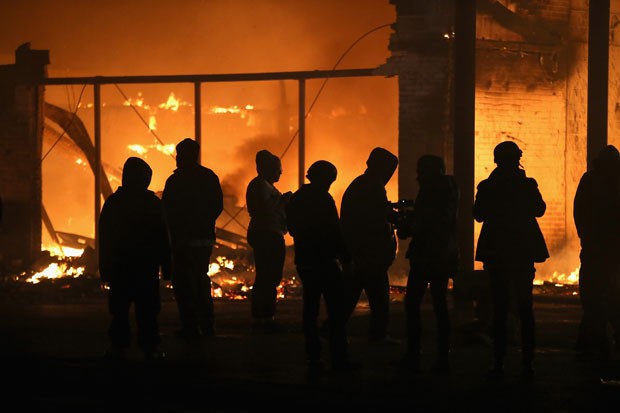 Manifestantes olham prédio pegar fogo durante protesto na madrugada desta terça-feira (25) em Ferguson (Foto: Wilson. Scott Olson/Getty Images/AFP)