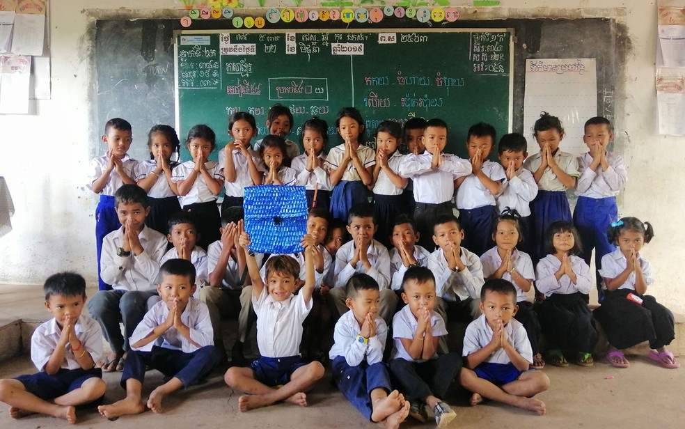 Ny, com a mochila de plástico feita pelo pai, ao lado dos colegas de turma na escola no Camboja — Foto: Reprodução/Facebook/Sophous Suon