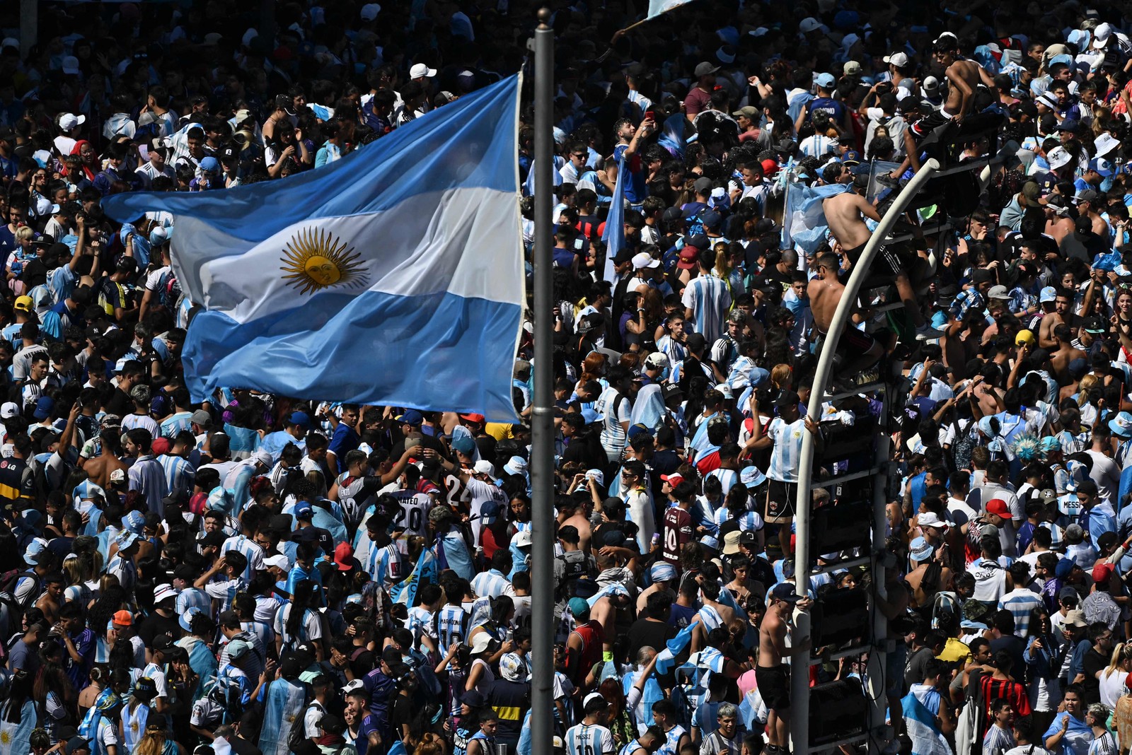 orcedores da Argentina esperam o ônibus com os jogadores da Argentina para passar pelo Obelisco para comemorar após vencer a Copa do Mundo do Catar 2022 em Buenos Aires — Foto: Luis ROBAYO / AFP