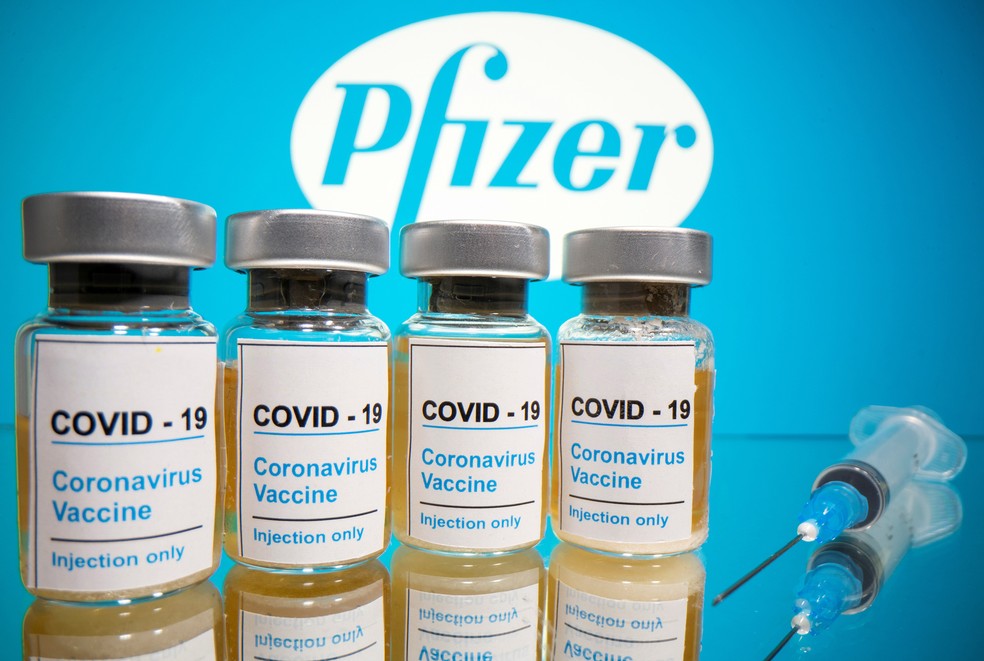Foto ilustrativa com frascos e seringa na frente de logotipo da farmacêutica Pfizer — Foto: Dado Ruvic/Reuters