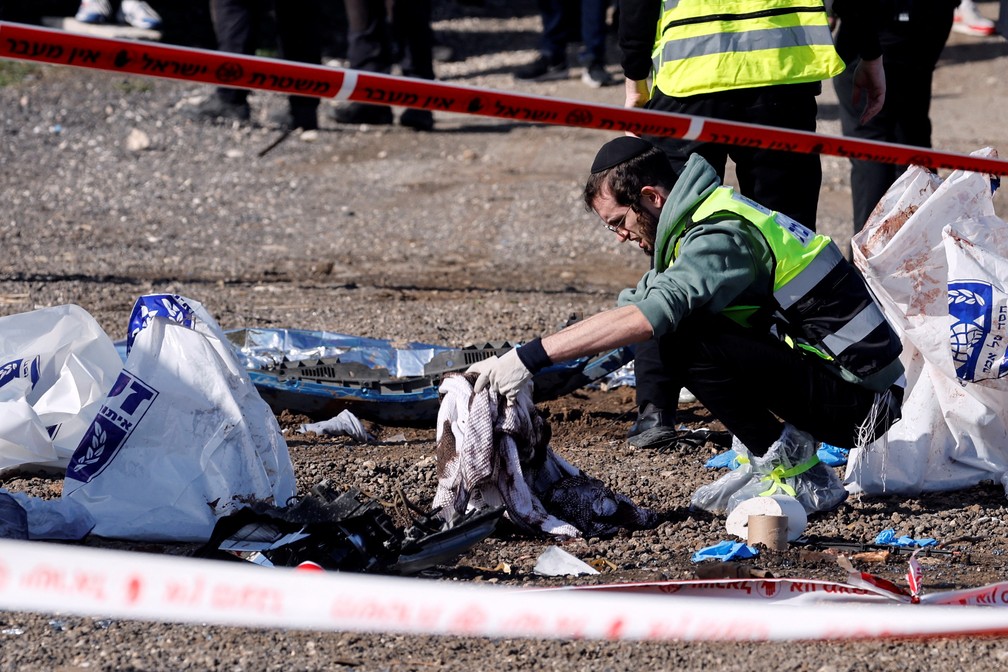 Membro da equipe de resgate israelense limpa manchas de sangue em ponto de ônibus onde um suposto ataque ocorreu em Jerusalém, em 10 de fevereiro de 2023 — Foto: REUTERS/Ammar Awad