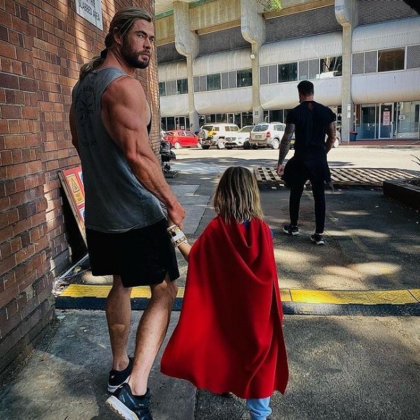 O ator Chris Hemsworth passeando com um dos filhos em foto que chamou atenção pelo contraste entre seus músculos dos braços e das pernas (Foto: Instagram)