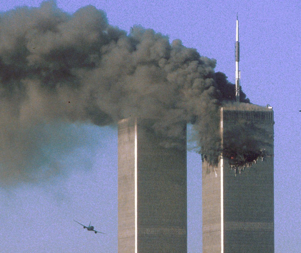 Segundos antes, avião do voo 175 da United Airlines é visto se aproximando da Torre Sul do WTC, em Nova York, enquanto a Torre Norte pega fogo, durante os ataques terroristas do 11 de Setembro — Foto: Sean Adair/Reuters/Arquivo