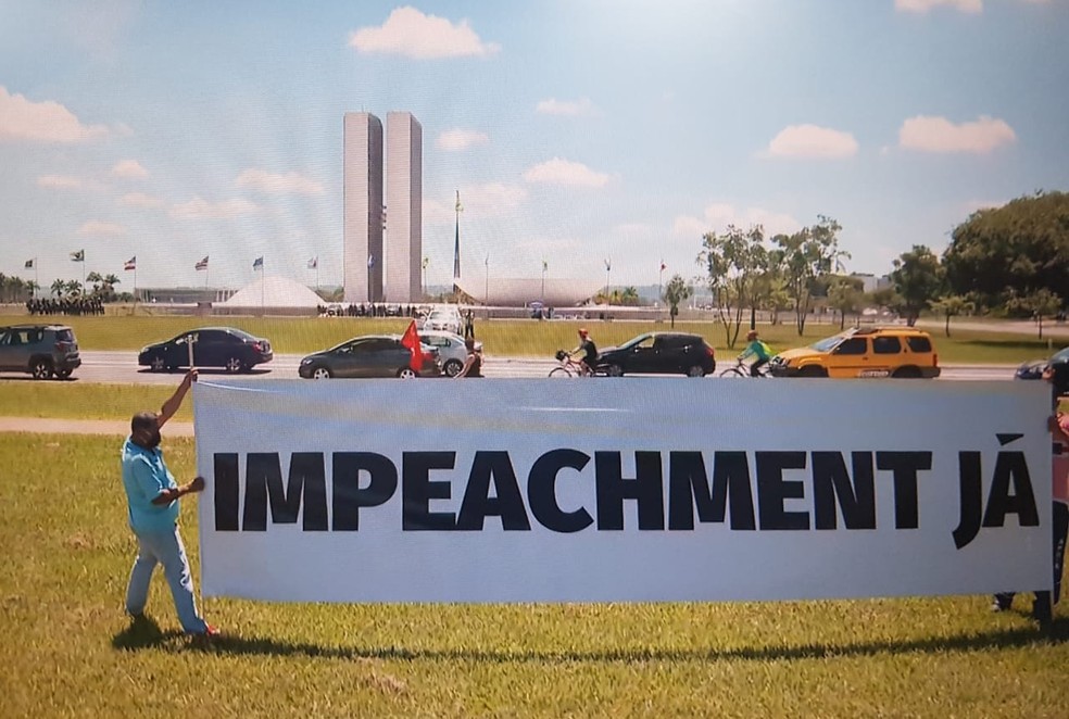 Manifestantes levantam faixa pedindo impeachment do presidente Jair Bolsonaro, em frente ao Congresso Nacional — Foto: TV Globo/Reprodução