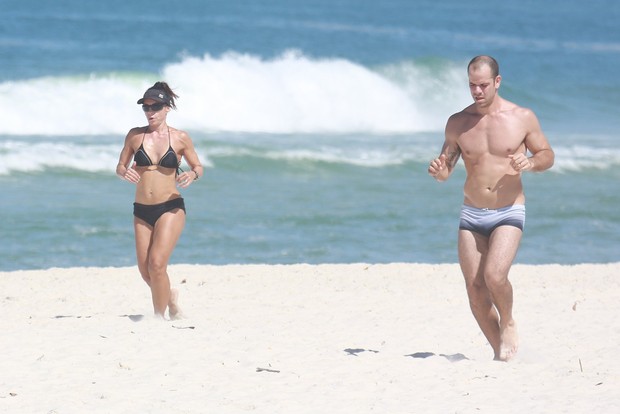 Carla Marins corre com seu marido na praia (Foto: Dilson Silva / Agnews)